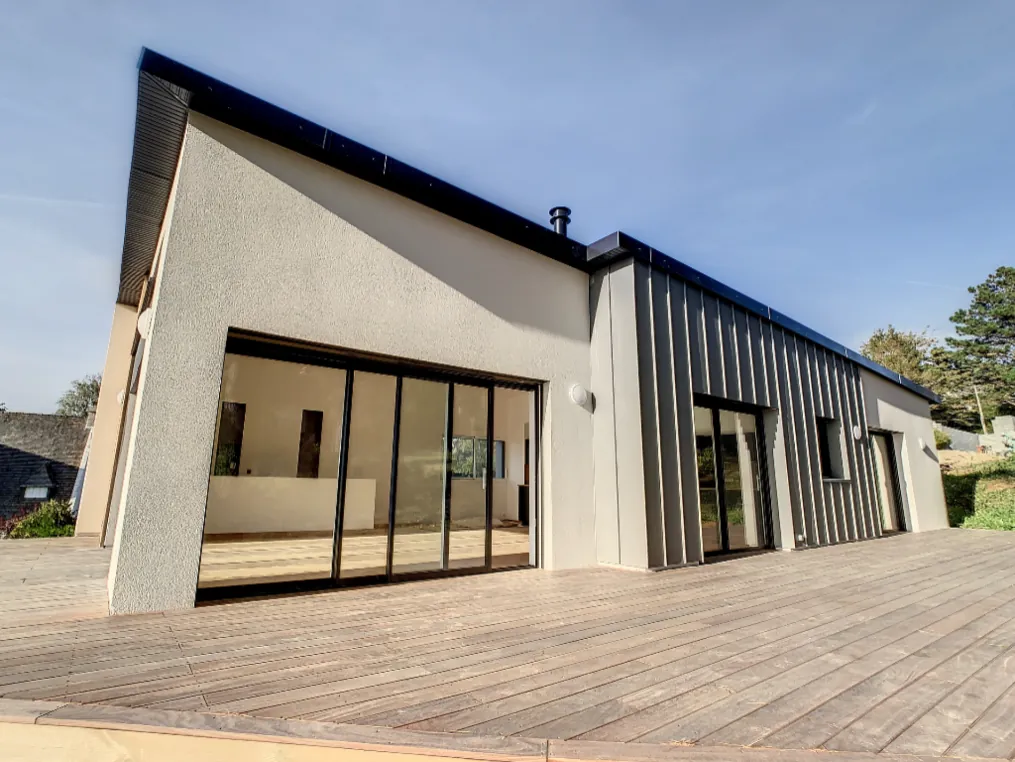 Maison contemporaine à toit monopente, enduit gris et bardage zinc, avec terrasse en bois, à Crozon