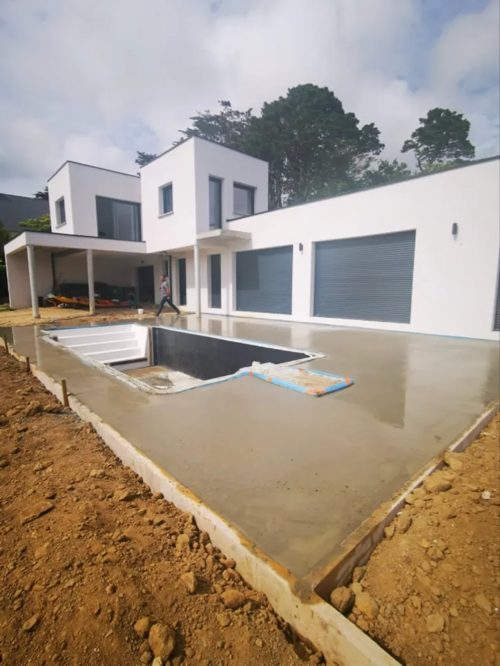 Maison contemporaine blanche et dalle béton autour d'une piscine à Plougonvelin